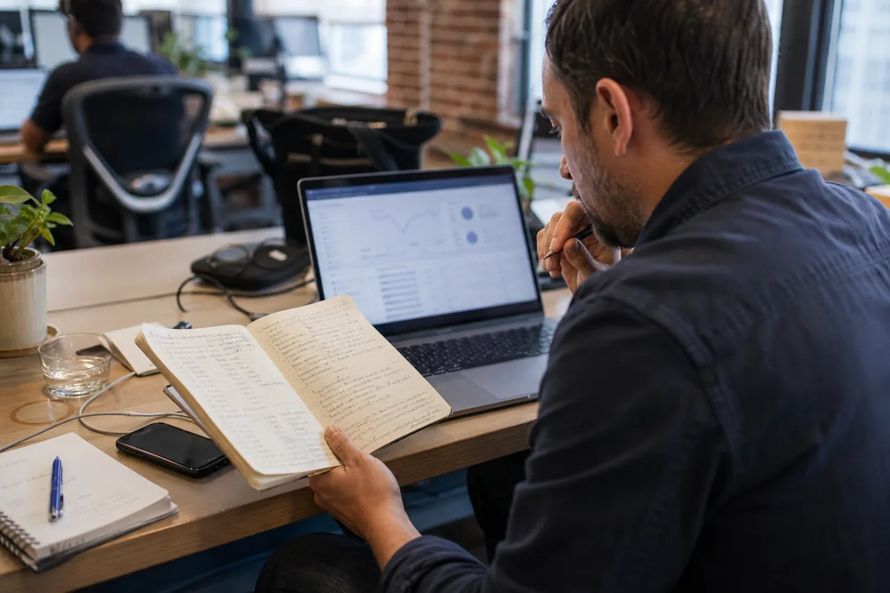 Person comparing laptop analytics with handwritten notes